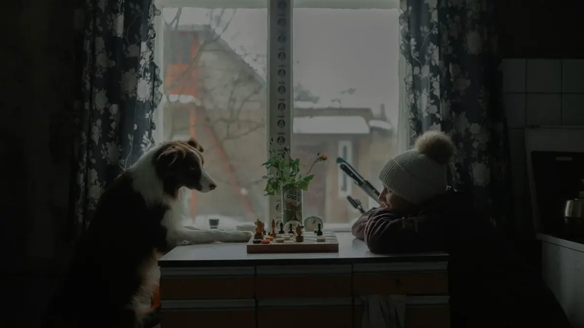 A dog eating from a stainless steel bowl in a home kitchen while an owner watches nearby